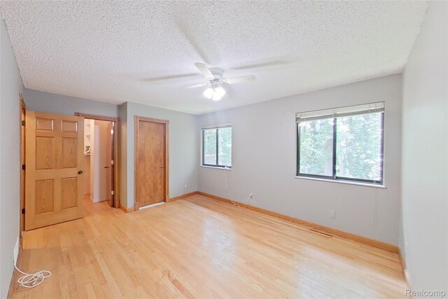 11589 Lombardy Ct, Pinckney, MI 48169 - unfurnished bedroom with light wood-style flooring, a textured ceiling, a closet, and a ceiling fan