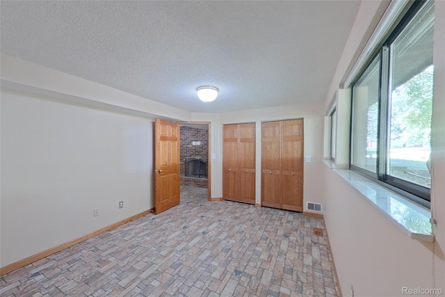 11589 Lombardy Ct, Pinckney, MI 48169 - unfurnished bedroom featuring a brick fireplace, two closets, and a textured ceiling