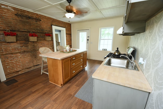 514 N Kalamazoo St, Paw Paw, MI 49079 - kitchen featuring dark wood-style floors, brown cabinets, a ceiling fan, a kitchen bar, and brick wall