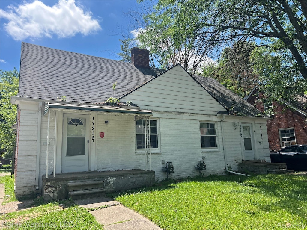 17210-12 Sioux St, Grosse Pointe, MI 48224 - view of front of house featuring a chimney, a front yard, brick siding, and roof with shingles