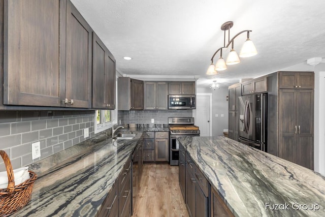 3268 Michele Ln, Hamilton, MI 49419 - kitchen with appliances with stainless steel finishes, tasteful backsplash, light wood-style floors, dark stone counters, and pendant lighting