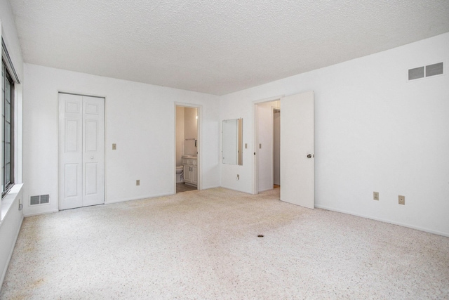 3841 Greenleaf Cir, Kalamazoo, MI 49008 - unfurnished bedroom with connected bathroom, a textured ceiling, and a closet