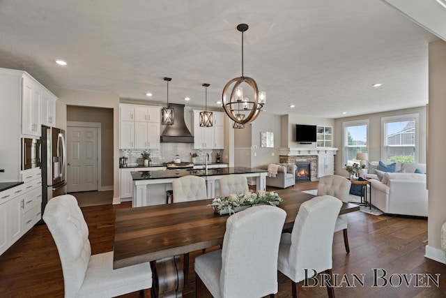 9633 Waterstone Dr, Byron Center, MI 49315 - dining area featuring dark wood-style flooring, recessed lighting, a fireplace, and a chandelier