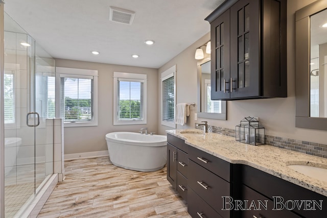 9633 Waterstone Dr, Byron Center, MI 49315 - bathroom with a shower stall, a soaking tub, double vanity, wood finished floors, and recessed lighting