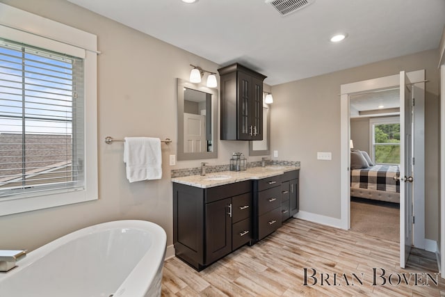 9633 Waterstone Dr, Byron Center, MI 49315 - full bath with a freestanding tub, double vanity, wood finished floors, recessed lighting, and ensuite bathroom