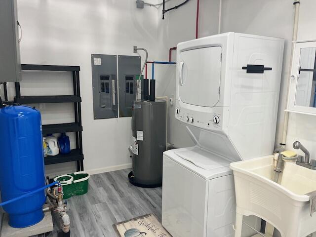 4969 N Highbridge Rd, Brethren, MI 49619 - laundry room with stacked washer / drying machine, water heater, electric panel, and wood finished floors