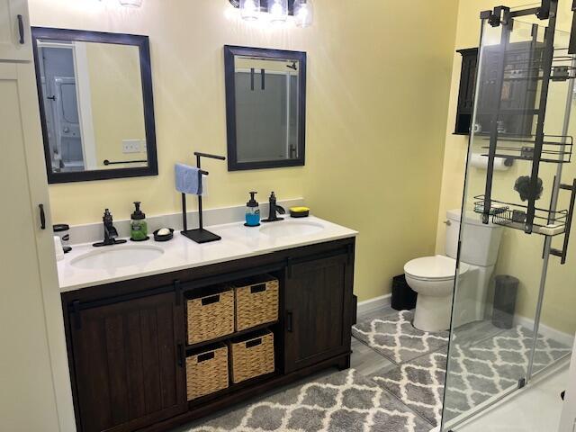 4969 N Highbridge Rd, Brethren, MI 49619 - bathroom featuring double vanity, a shower with shower door, and wood finished floors