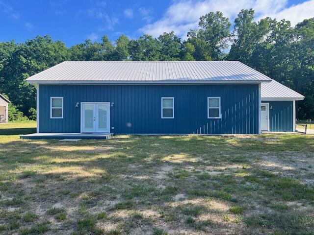 4969 N Highbridge Rd, Brethren, MI 49619 - back of house featuring french doors, board and batten siding, a lawn, and a metal roof