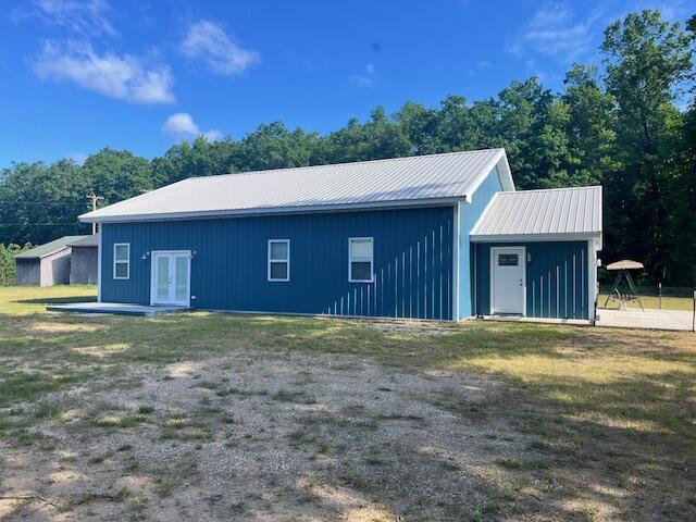 4969 N Highbridge Rd, Brethren, MI 49619 - back of house with french doors, board and batten siding, a yard, and a metal roof