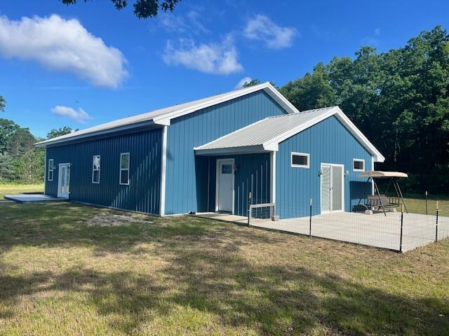 4969 N Highbridge Rd, Brethren, MI 49619 - back of house featuring a yard, a metal roof, and a patio