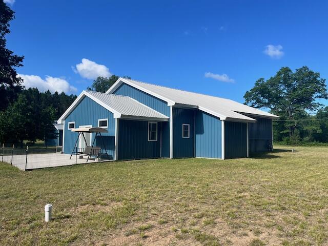 4969 N Highbridge Rd, Brethren, MI 49619 - view of side of property featuring a lawn, a patio area, and a metal roof