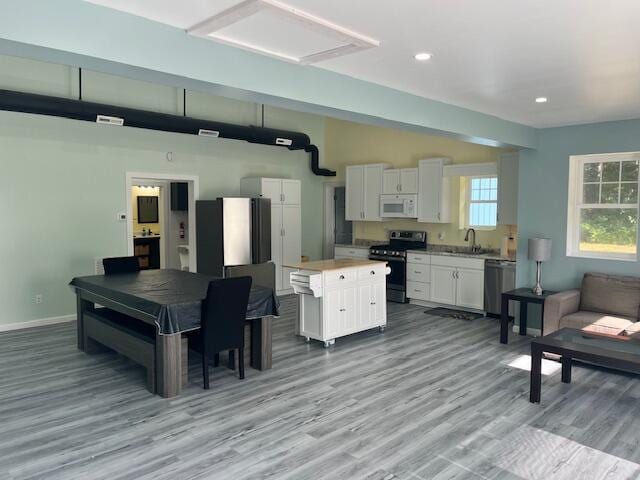 4969 N Highbridge Rd, Brethren, MI 49619 - kitchen featuring electric range, white microwave, stainless steel dishwasher, white cabinets, and light wood-style flooring
