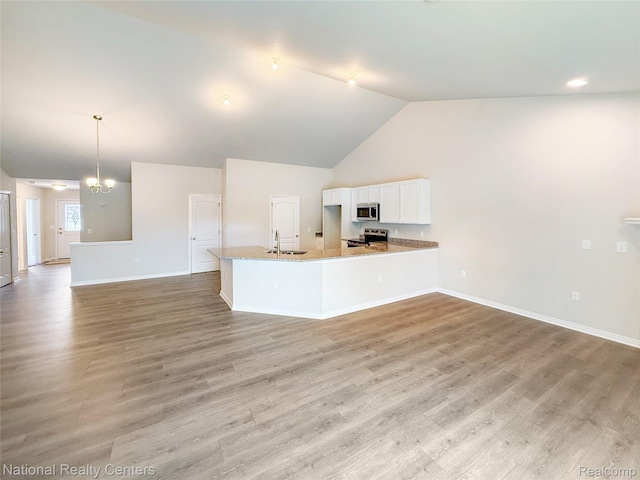 253 Devonshire Dr Unit 2, Lapeer, MI 48446 - kitchen with appliances with stainless steel finishes, white cabinets, open floor plan, high vaulted ceiling, and a peninsula