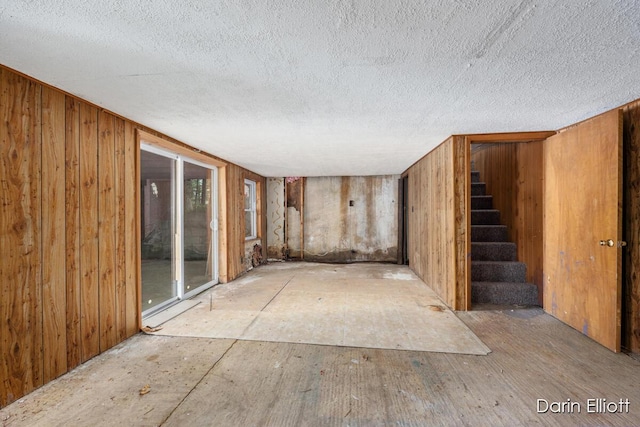 7985 Island View Dr, Newaygo, MI 49337 - below grade area featuring a textured ceiling, stairway, and wooden walls