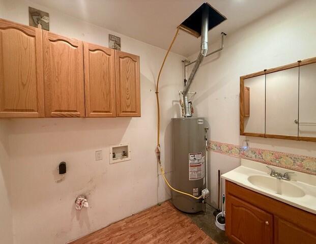 4807 118th Ave, Fennville, MI 49408 - laundry area with water heater, hookup for a washing machine, light wood finished floors, and cabinet space