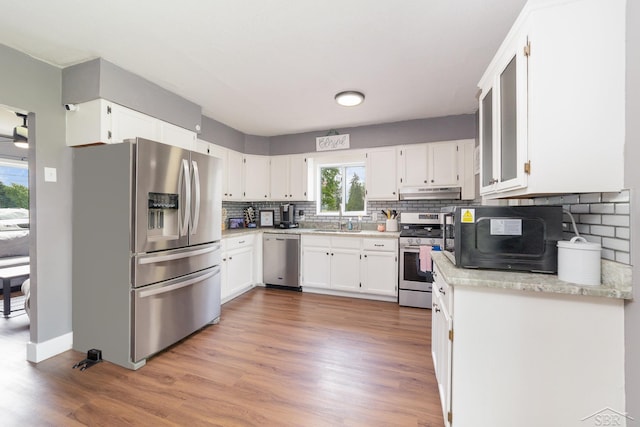 14079 Elms Rd, Montrose, MI 48457 - kitchen with stainless steel appliances, under cabinet range hood, backsplash, white cabinets, and wood finished floors