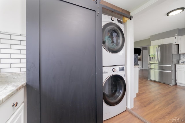 14079 Elms Rd, Montrose, MI 48457 - laundry area featuring stacked washer and clothes dryer, light wood finished floors, and a barn door