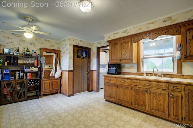 3092 Dillon Rd, Flushing, MI 48433 - kitchen featuring wallpapered walls, a wainscoted wall, washer / dryer, a ceiling fan, and brown cabinets