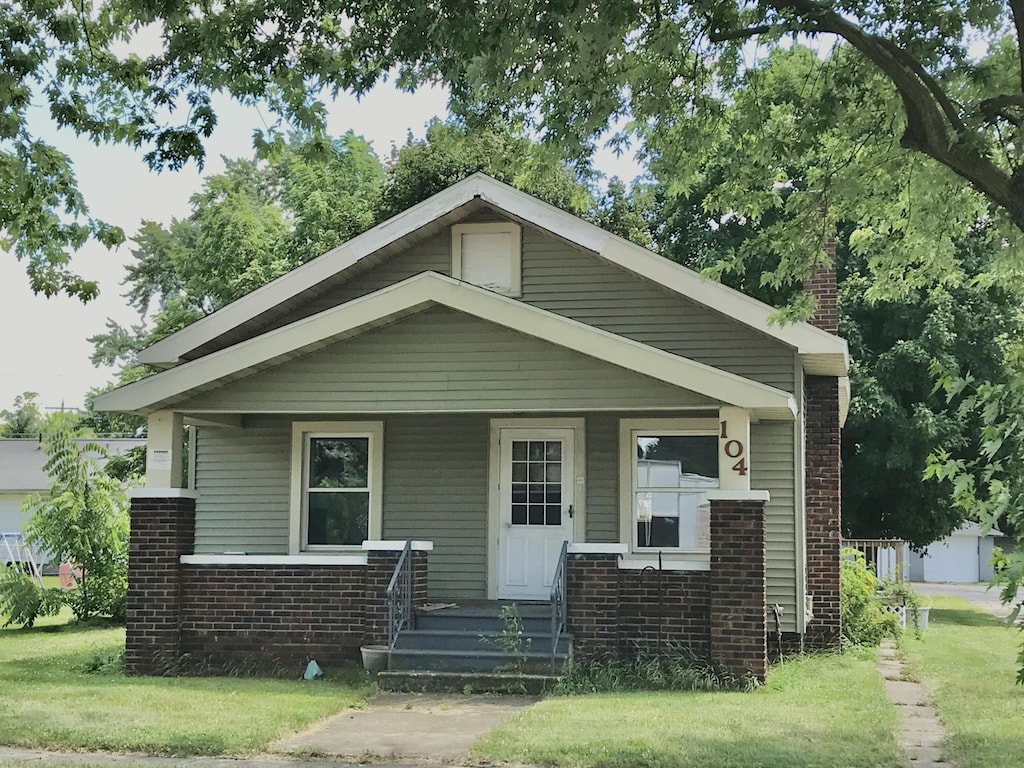 104 N Kalamazoo St, White Pigeon, MI 49099 - bungalow-style house with brick siding, a porch, and a chimney