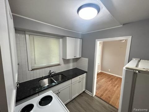 15452 Southfield Rd, Detroit, MI 48223 - kitchen featuring dark wood-type flooring, white cabinetry, decorative backsplash, washer / clothes dryer, and dark countertops