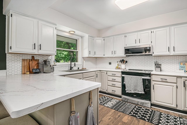 3042 Kevin St, Saint Joseph, MI 49085 - kitchen with appliances with stainless steel finishes, a peninsula, white cabinetry, and wood finished floors
