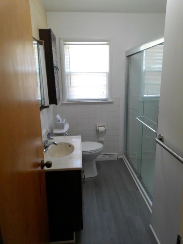 1602 Blakely Ave, Jackson, MI 49202 - bathroom with a shower stall, vanity, tile walls, wood finished floors, and a baseboard heating unit