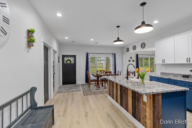 412 S Woodworth St, Corunna, MI 48817 - kitchen with white cabinets, blue cabinetry, recessed lighting, light wood finished floors, and a center island with sink