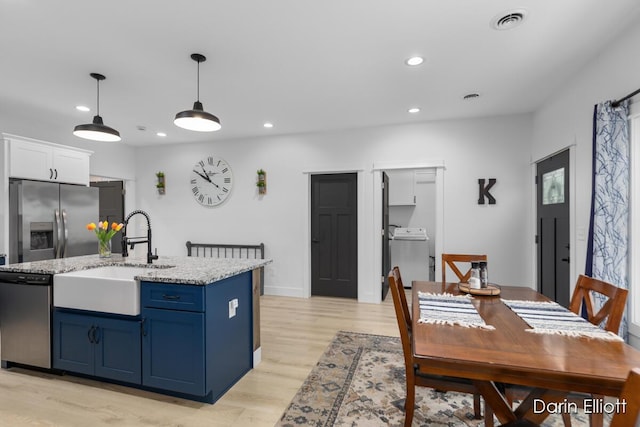412 S Woodworth St, Corunna, MI 48817 - kitchen featuring stainless steel appliances, washer / dryer, blue cabinetry, recessed lighting, and light wood-style floors