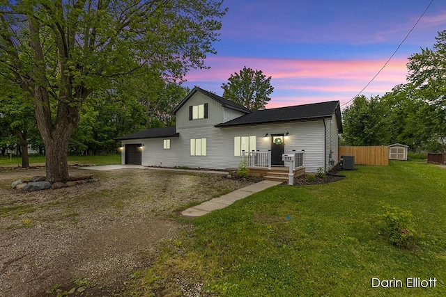 412 S Woodworth St, Corunna, MI 48817 - back of house at dusk featuring concrete driveway, a shed, an attached garage, and a yard