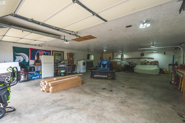 1684 W W County Line Rd, Sand Lake, MI 49343 - garage featuring freestanding refrigerator, washer / clothes dryer, and a workshop area