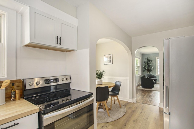 185 W 21st St, Holland, MI 49423 - kitchen featuring appliances with stainless steel finishes, arched walkways, light wood-style flooring, wooden counters, and white cabinetry