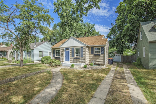 185 W 21st St, Holland, MI 49423 - bungalow-style house featuring an outbuilding, a front yard, a shingled roof, a detached garage, and driveway