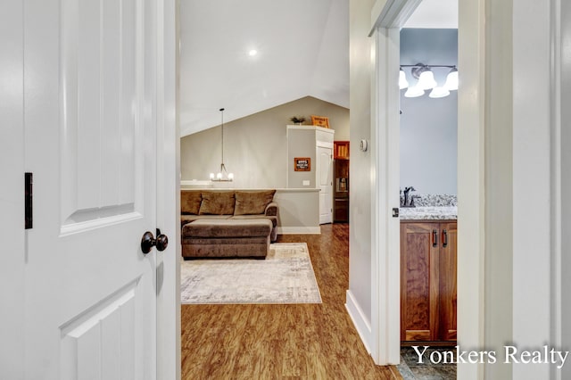 4005 Bullseye Ln, Dorr, MI 49323 - hallway featuring lofted ceiling, a chandelier, and wood finished floors