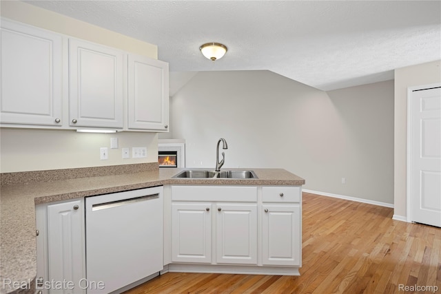 480 Hosta, Howell, MI 48843 - kitchen featuring white dishwasher, white cabinets, a peninsula, light wood-type flooring, and a glass covered fireplace