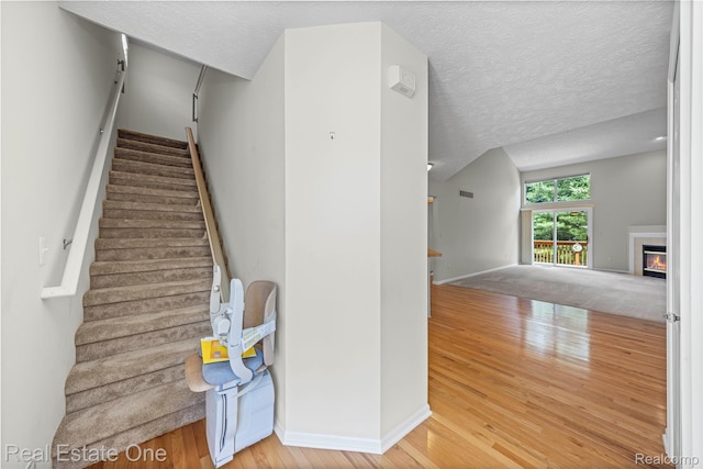 480 Hosta, Howell, MI 48843 - stairway with wood finished floors, a textured ceiling, and a glass covered fireplace