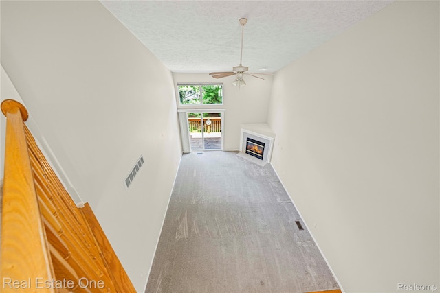 480 Hosta, Howell, MI 48843 - unfurnished living room with a textured ceiling, ceiling fan, a fireplace with flush hearth, and carpet flooring