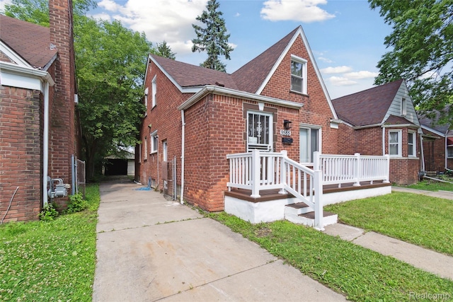 9585 Asbury Park, Detroit, MI 48227 - tudor-style house with brick siding, a front yard, a shingled roof, and driveway