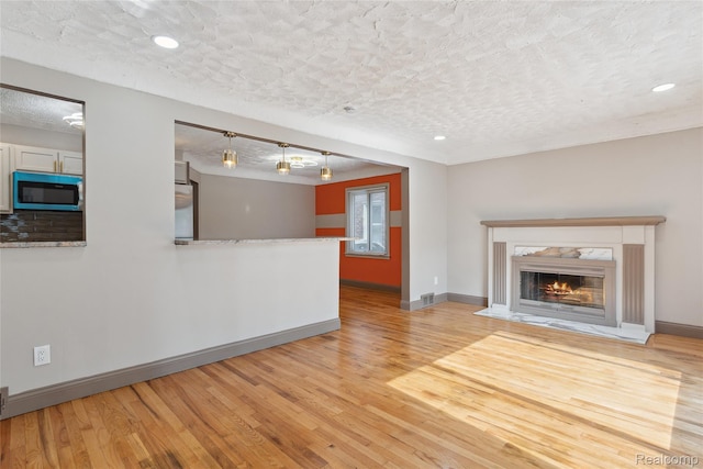 9585 Asbury Park, Detroit, MI 48227 - unfurnished living room featuring a textured ceiling, light wood-style flooring, a high end fireplace, and recessed lighting