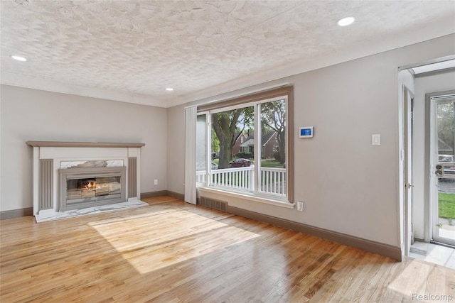 9585 Asbury Park, Detroit, MI 48227 - unfurnished living room featuring healthy amount of natural light, wood finished floors, a high end fireplace, recessed lighting, and a textured ceiling