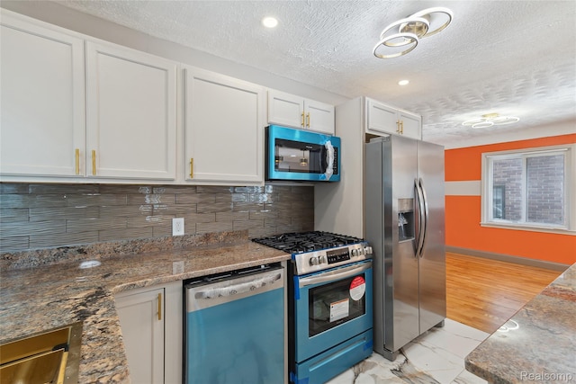 9585 Asbury Park, Detroit, MI 48227 - kitchen with appliances with stainless steel finishes, white cabinets, a textured ceiling, decorative backsplash, and stone counters