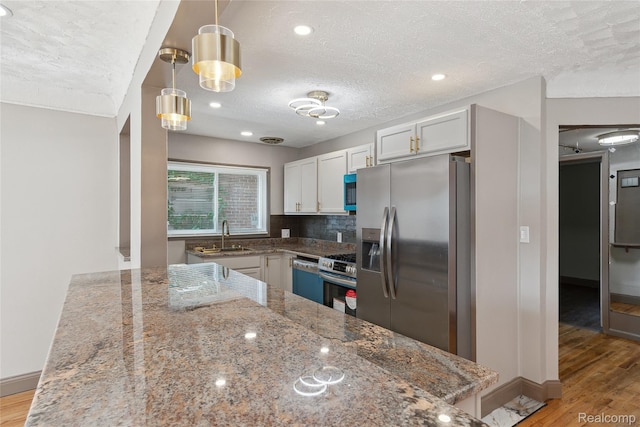 9585 Asbury Park, Detroit, MI 48227 - kitchen featuring appliances with stainless steel finishes, a textured ceiling, light wood-style floors, stone counters, and backsplash