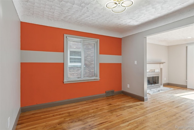 9585 Asbury Park, Detroit, MI 48227 - spare room featuring wood finished floors, a textured ceiling, a high end fireplace, and a chandelier
