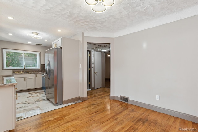 9585 Asbury Park, Detroit, MI 48227 - kitchen featuring stainless steel refrigerator with ice dispenser, light wood finished floors, a textured ceiling, white cabinetry, and recessed lighting