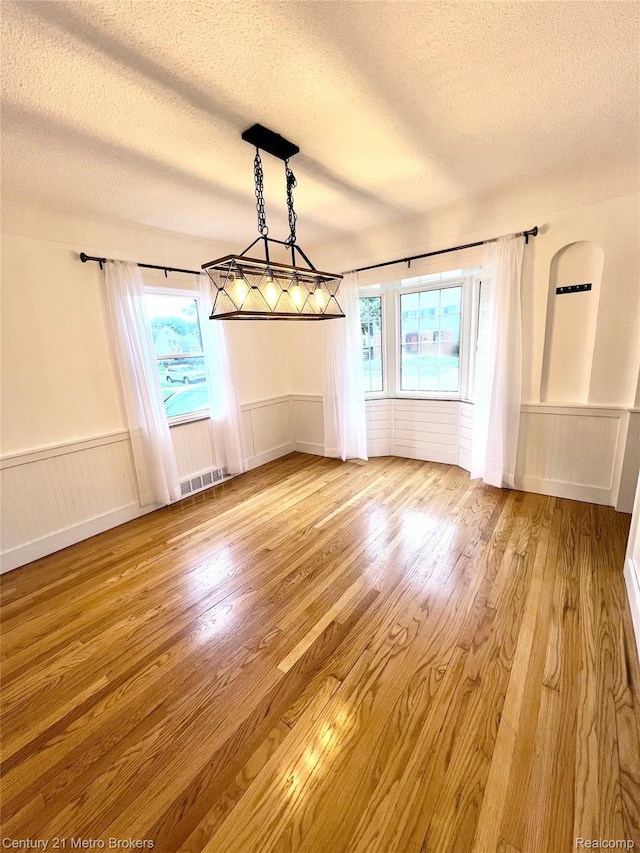 2122 Pierce St, Flint, MI 48503 - unfurnished dining area featuring a textured ceiling, wainscoting, and wood finished floors