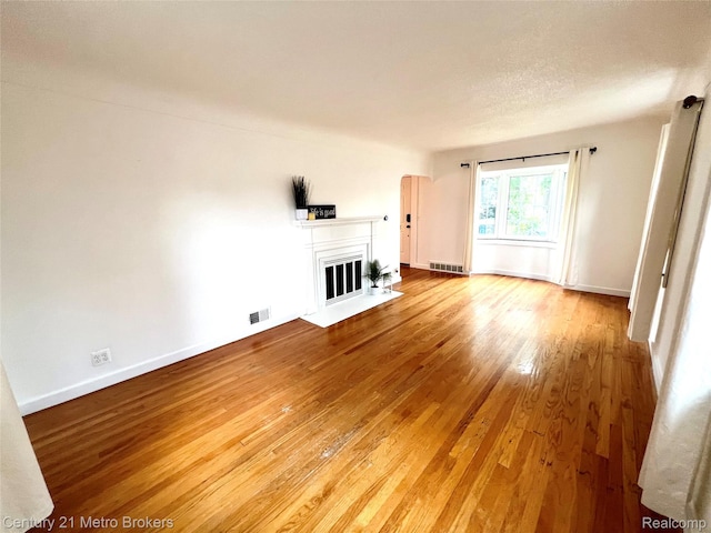 2122 Pierce St, Flint, MI 48503 - unfurnished living room featuring hardwood / wood-style floors, a fireplace with flush hearth, and arched walkways