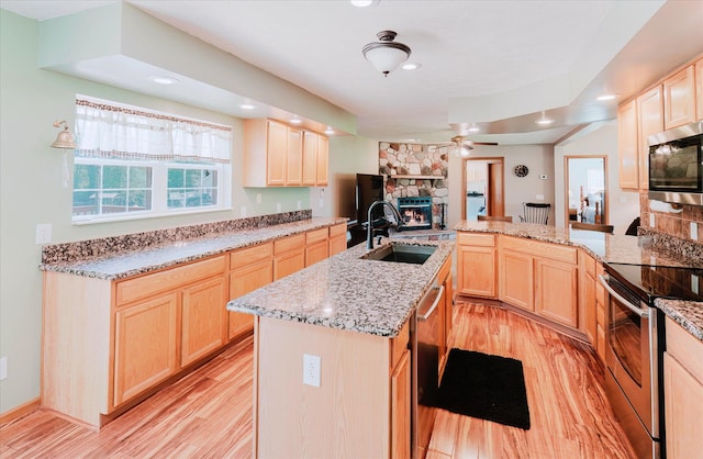 2098 Fisher Ct, Howell, MI 48855 - kitchen featuring stainless steel appliances, light brown cabinetry, light wood-style floors, a stone fireplace, and recessed lighting