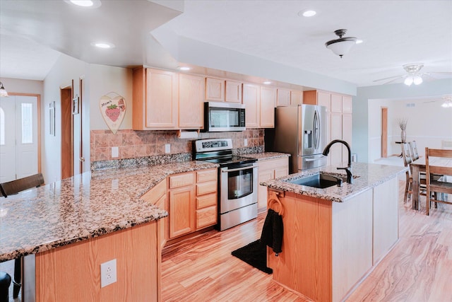 2098 Fisher Ct, Howell, MI 48855 - kitchen with appliances with stainless steel finishes, a peninsula, decorative backsplash, light brown cabinetry, and light wood finished floors