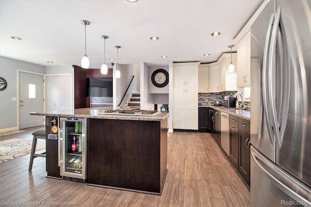 5885 Rockcroft Blvd, Clarkston, MI 48346 - kitchen with appliances with stainless steel finishes, wine cooler, a kitchen island, light wood-style floors, and recessed lighting