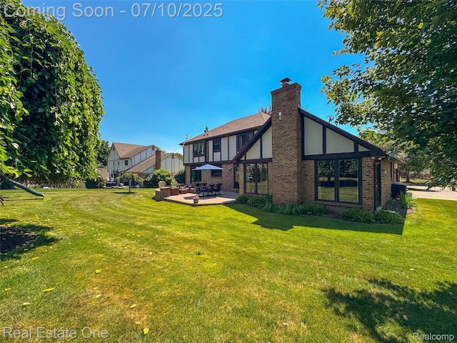 21653 Heatheridge Ln, Northville, MI 48167 - rear view of house with a yard, brick siding, a patio area, and a chimney