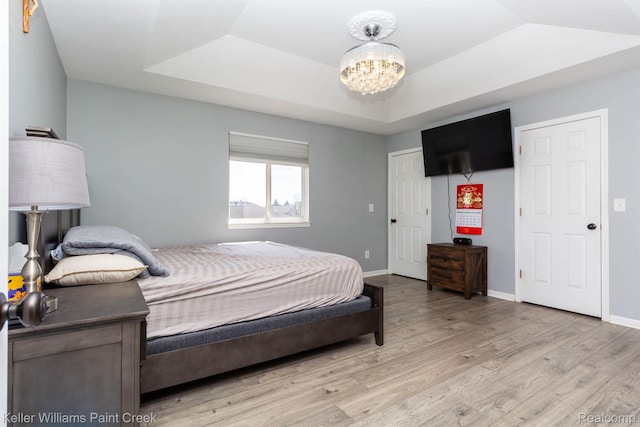 55856 Serene Dr, Macomb, MI 48042 - bedroom with a raised ceiling, light wood finished floors, and a chandelier